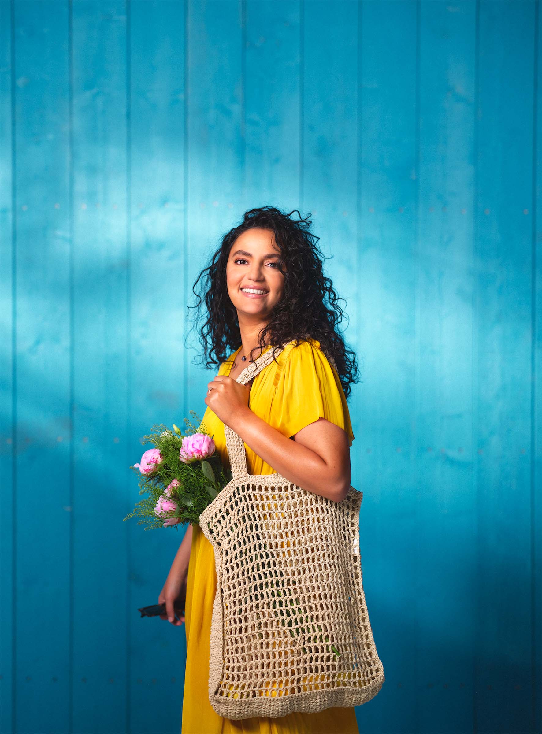 Kvinna med blommor och kasse mot en blå vägg