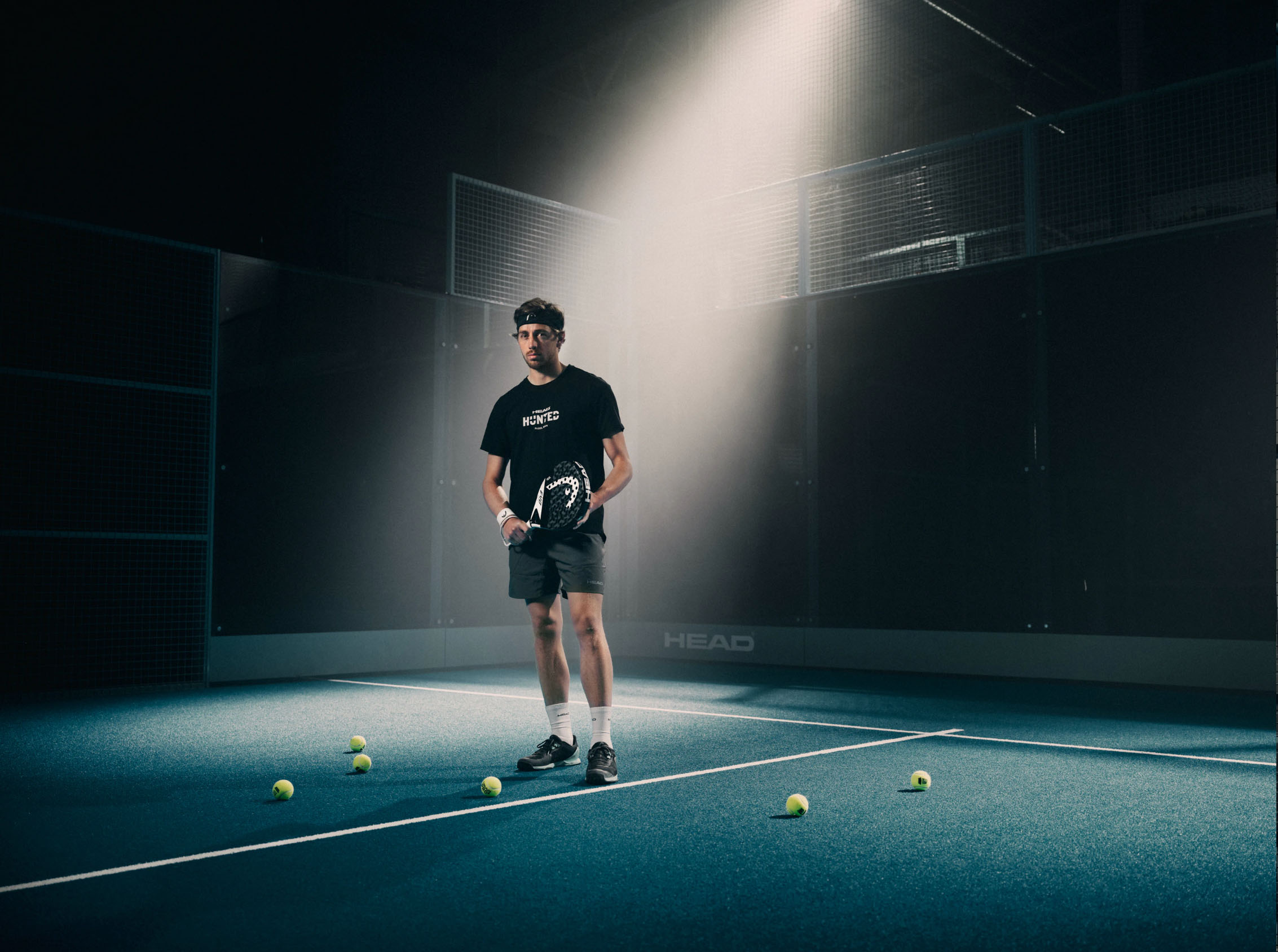 Padelspelare ensam på banan i ljuskägla