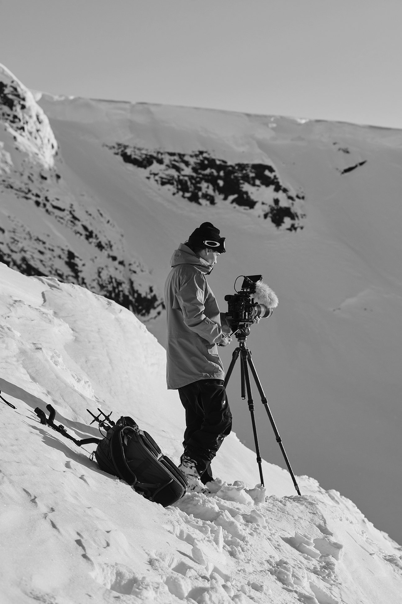 Fotograf med kamera på stativ i brant snösluttning