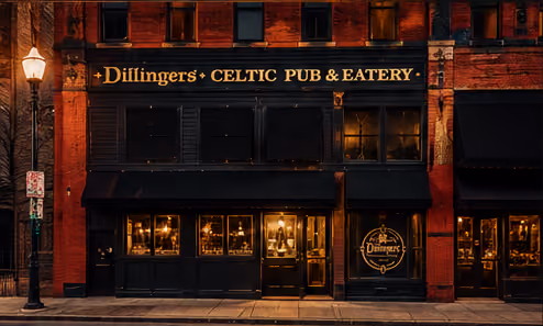 Nighttime exterior of Dillinger's Celtic Pub & Eatery with warm interior lights glowing through windows and a rustic brick facade.