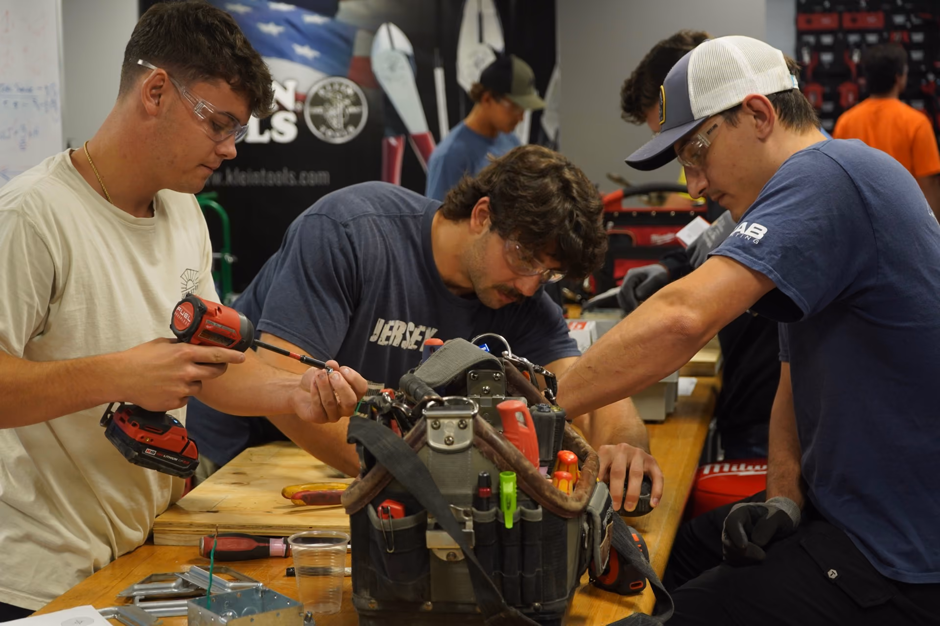 Apprentices working together on electrical equipment at a workbench