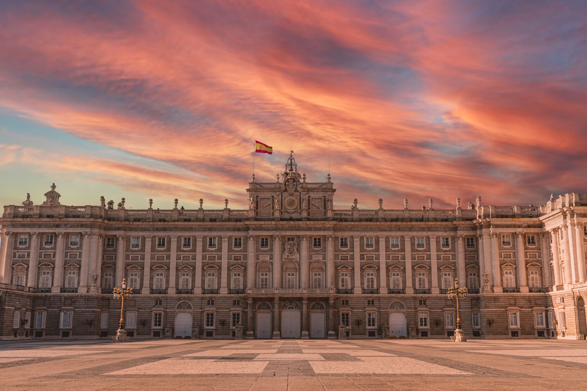 The Royal Palace of Madrid under a red sunset sky