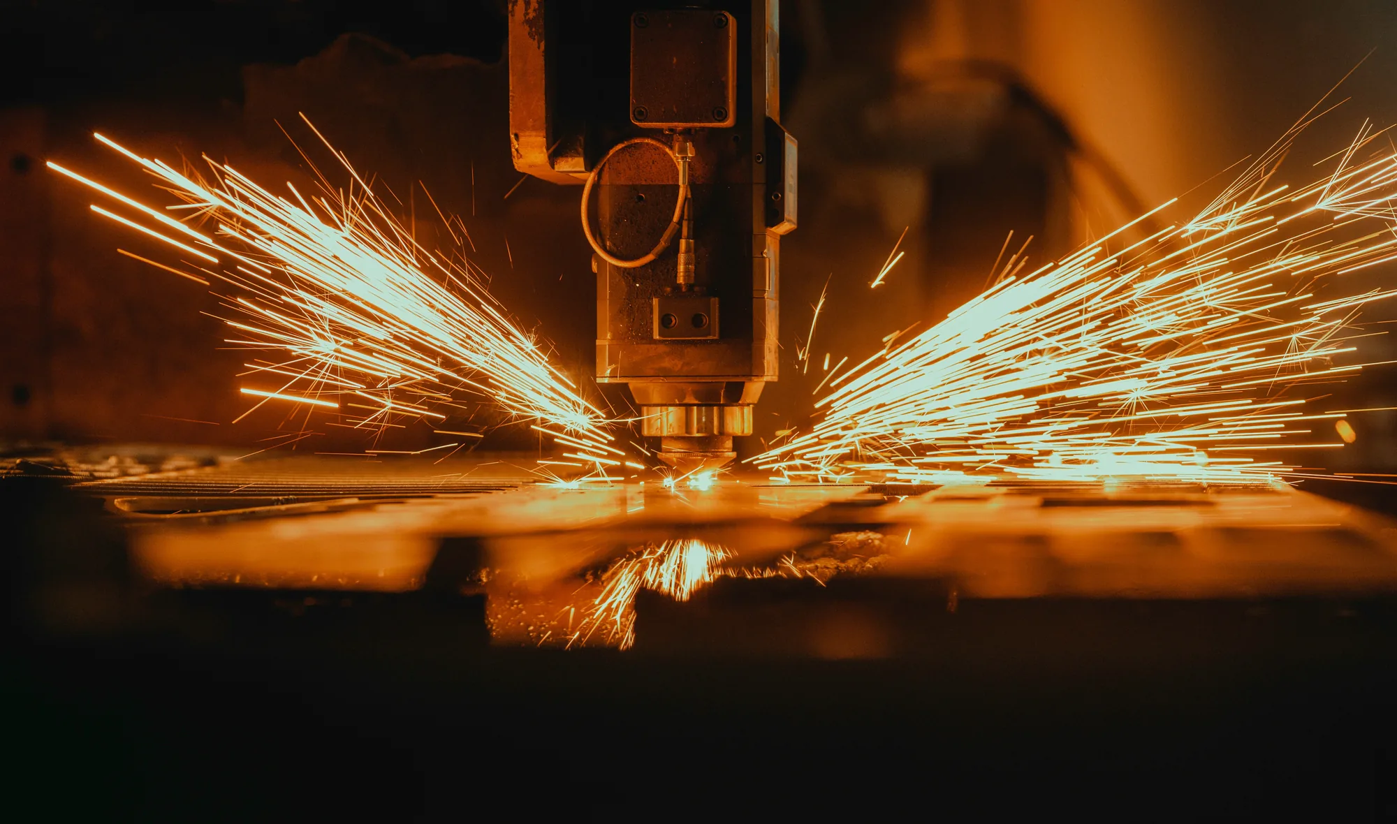 Laser cutter sending sparks across a steel sheet