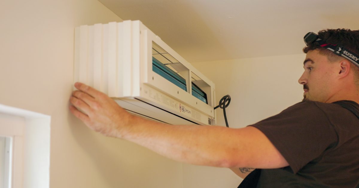 Installer mounting a ductless mini-split indoor unit