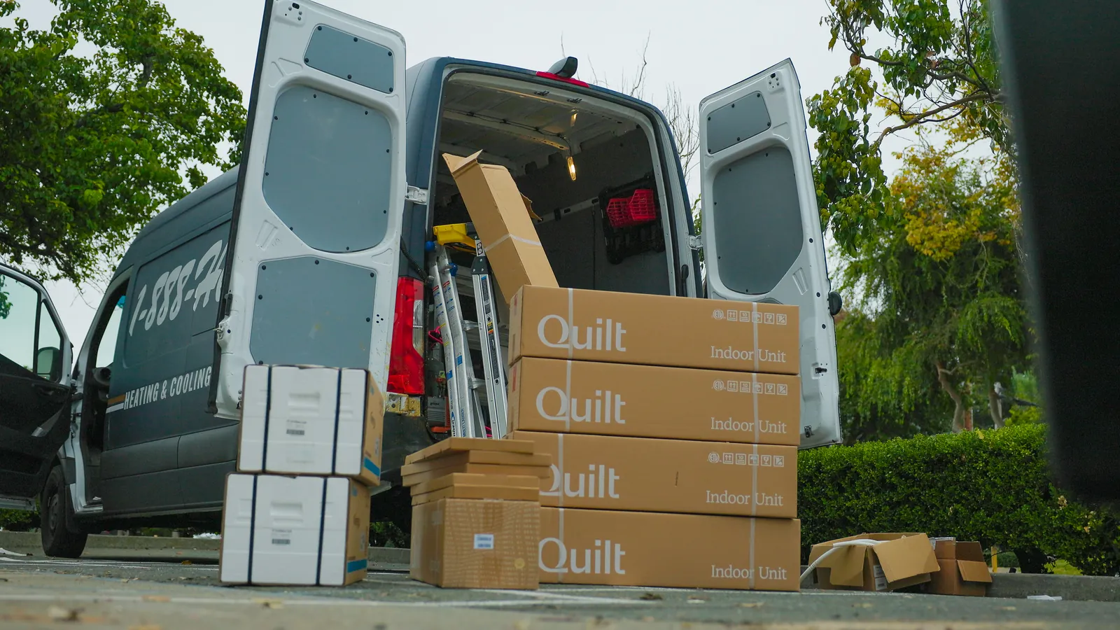 1-888-Heat-Pumps van with heat pump units stacked beside it, ready for installation