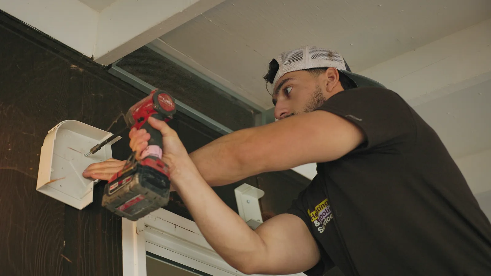Installer drilling a mounting bracket for a heat pump line set
