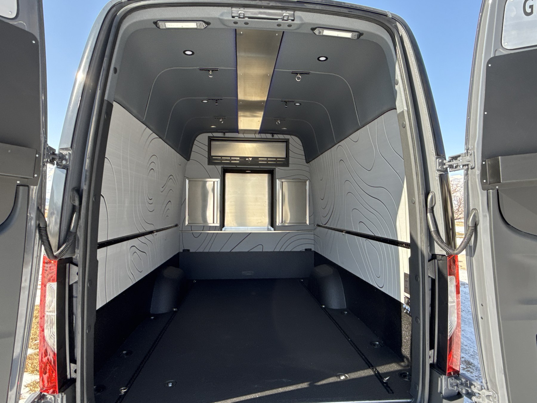 Open rear cargo area with topographic wall panels and tie-down tracks