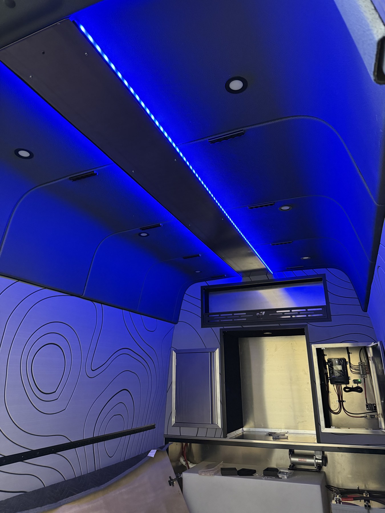 Blue LED lighting and metal cabinetry inside a custom van