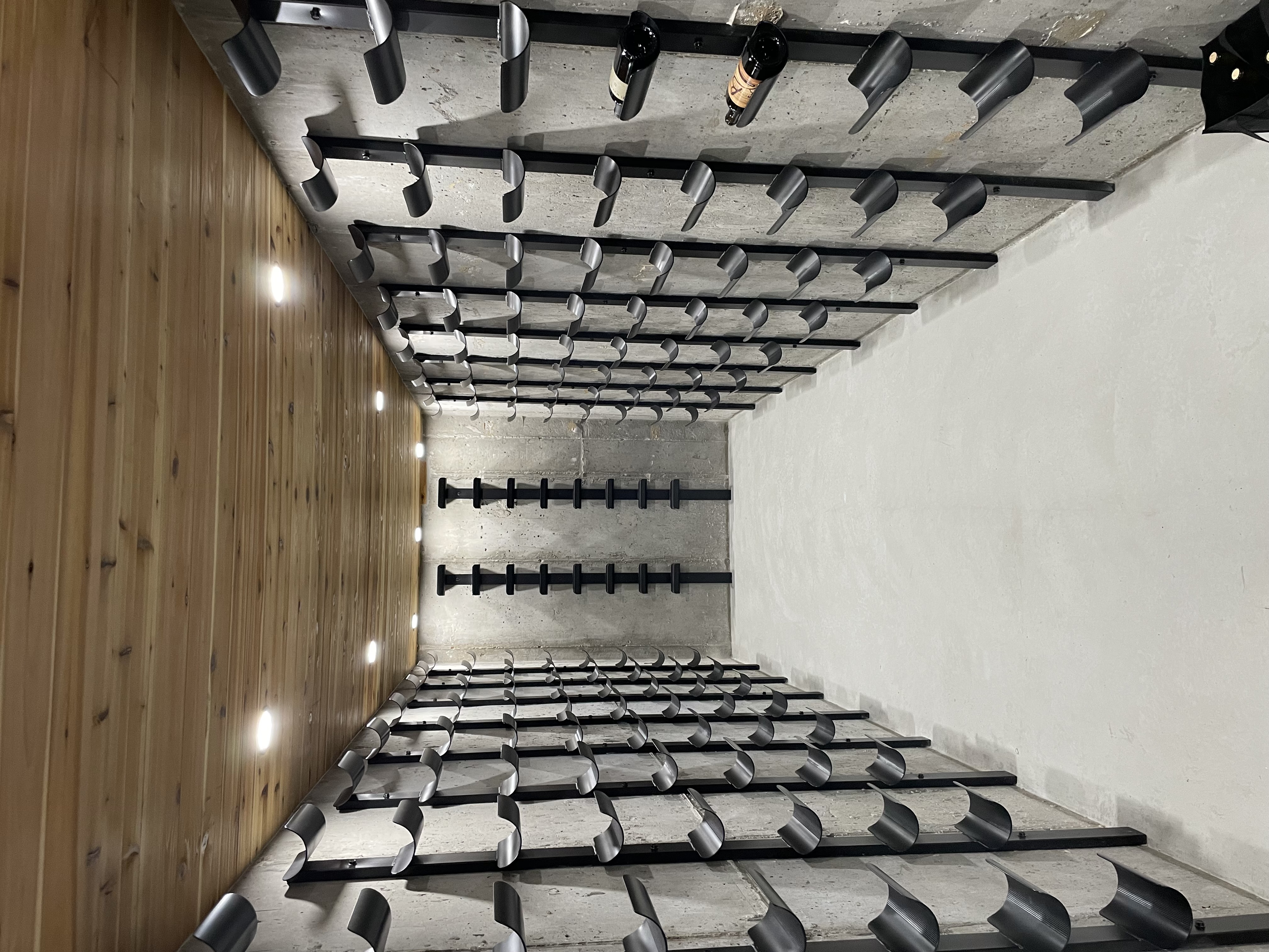 Custom black metal bottle cradles lining a wine cellar