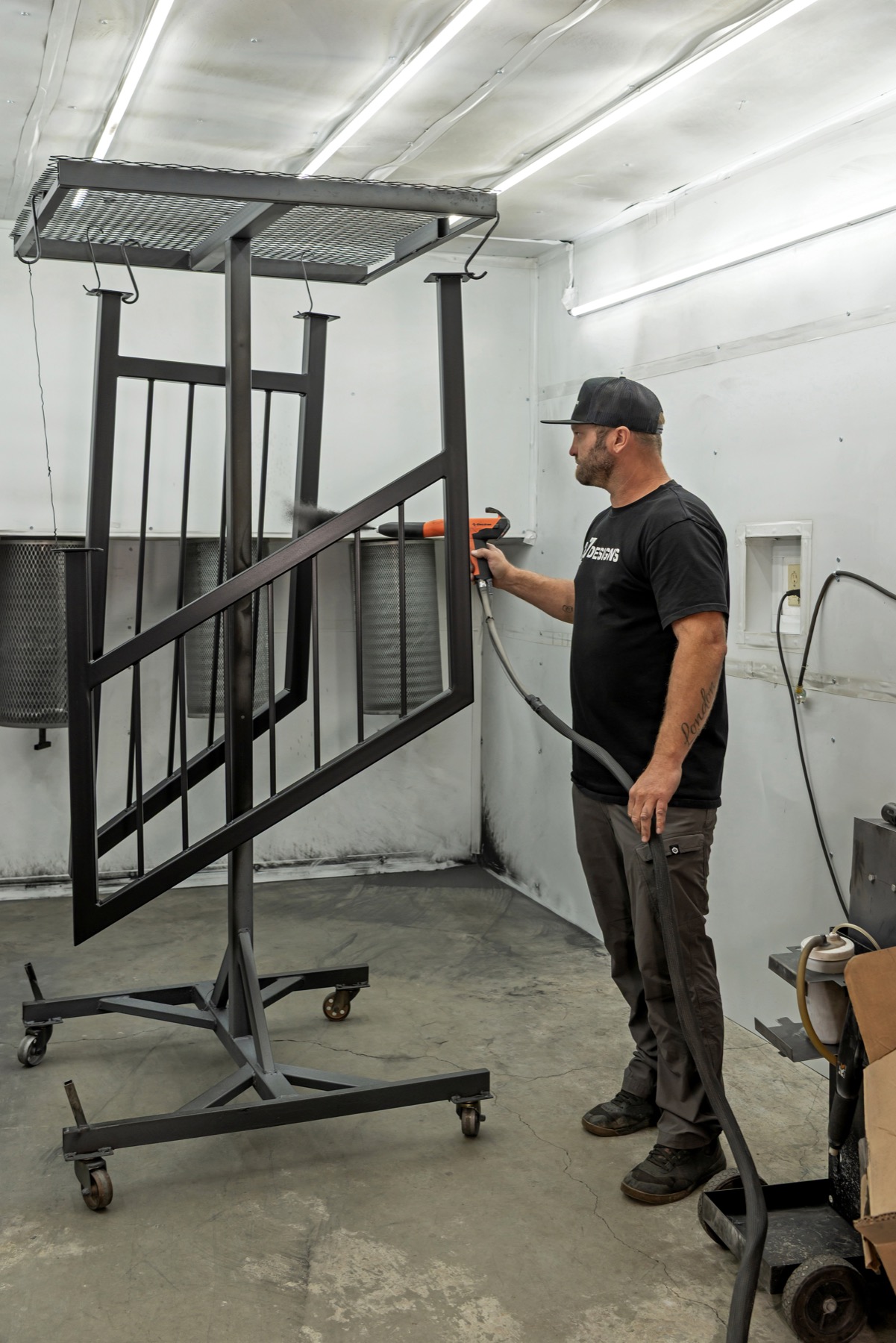 C2 Designs craftsman applying a finish to a custom steel railing in the workshop