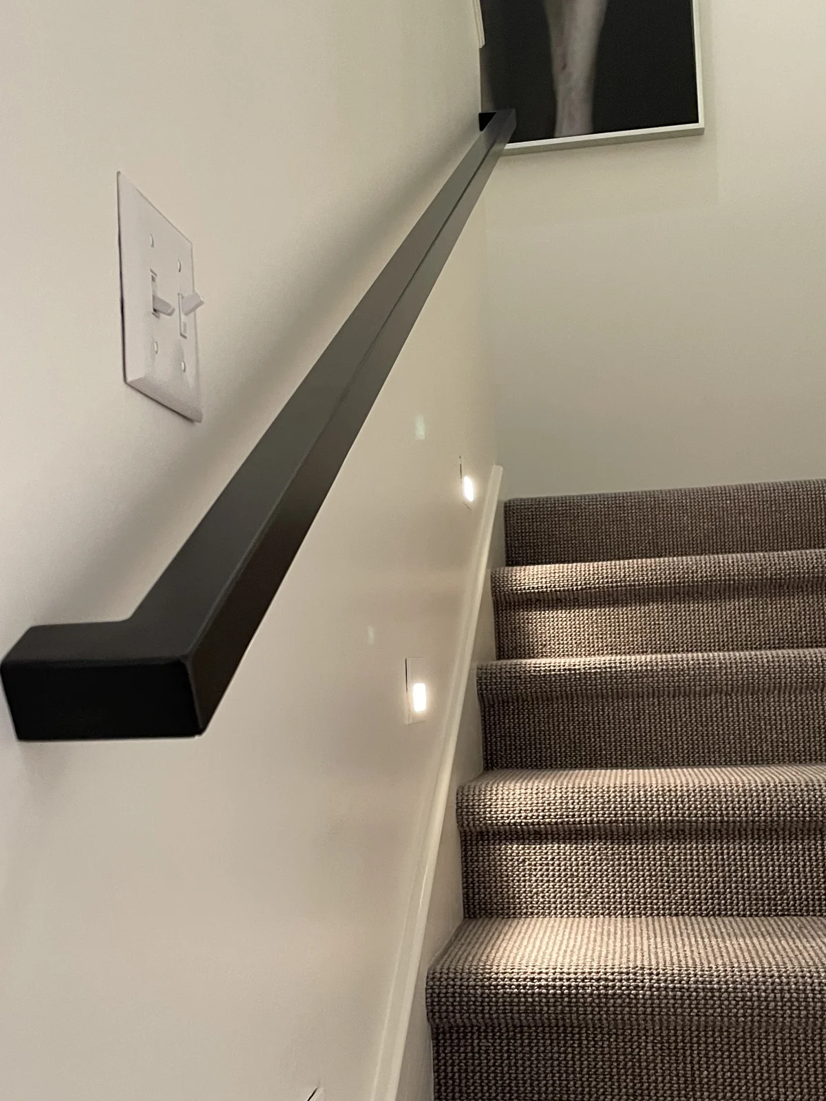 Close-up of a custom black metal handrail along an interior staircase