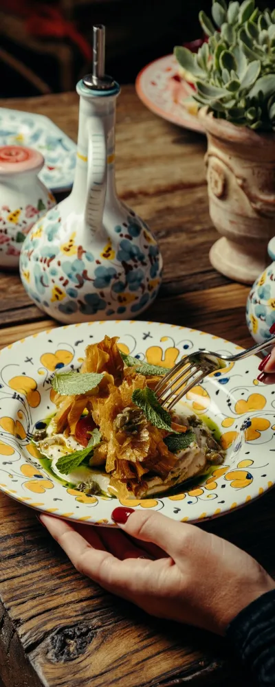 Assiette de pâtes dans une céramique peinte à la main, huilier et plante grasse, au restaurant italien à Megève