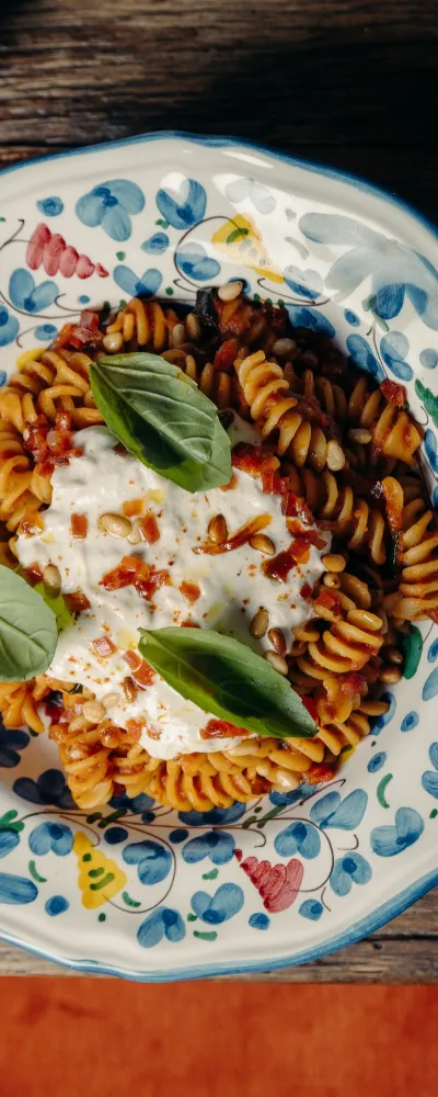 Fusilli à la sauce tomate, crème et basilic dans une assiette en céramique bleue au restaurant italien à Megève