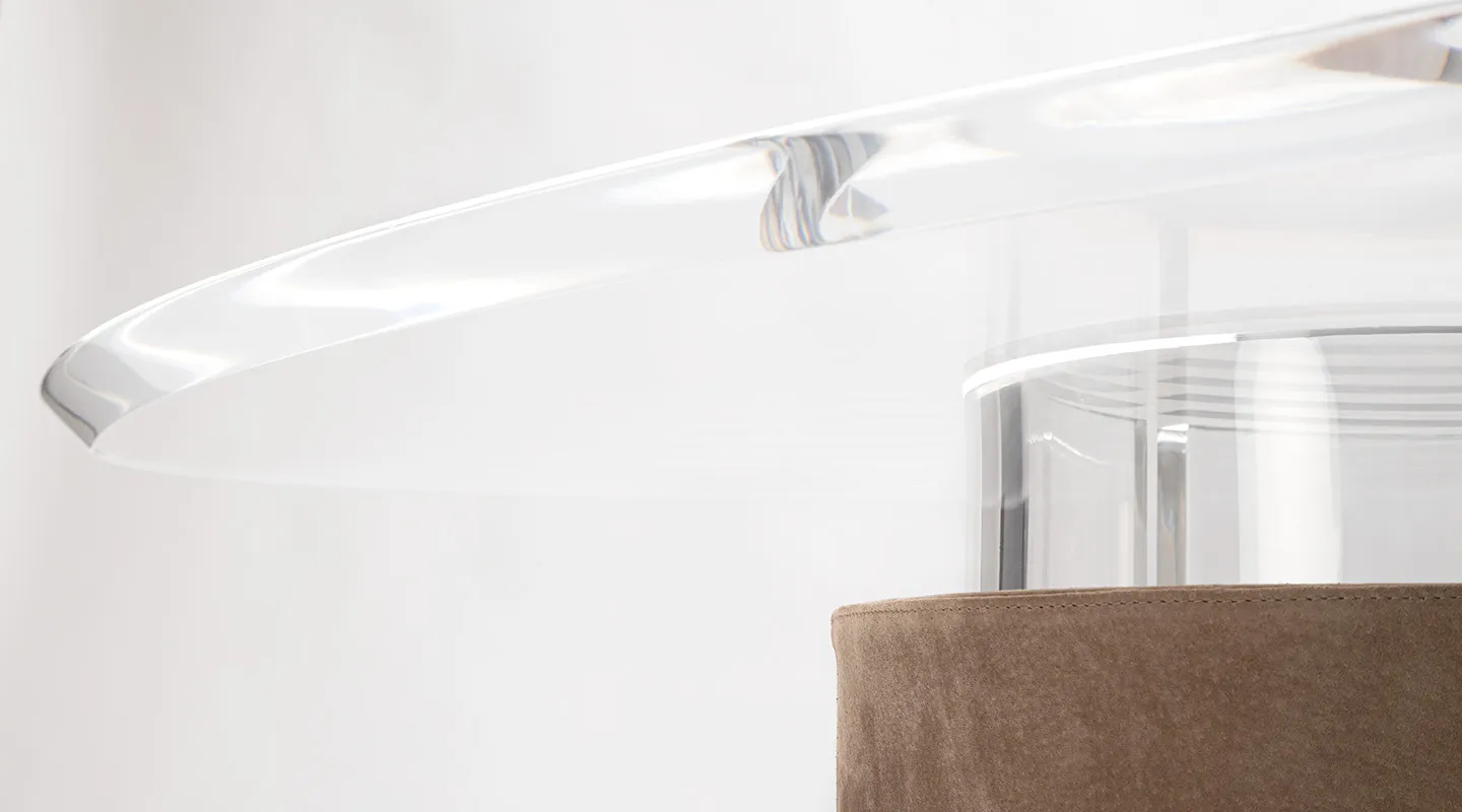 Close-up of a transparent glass tray with a brown suede base under it.