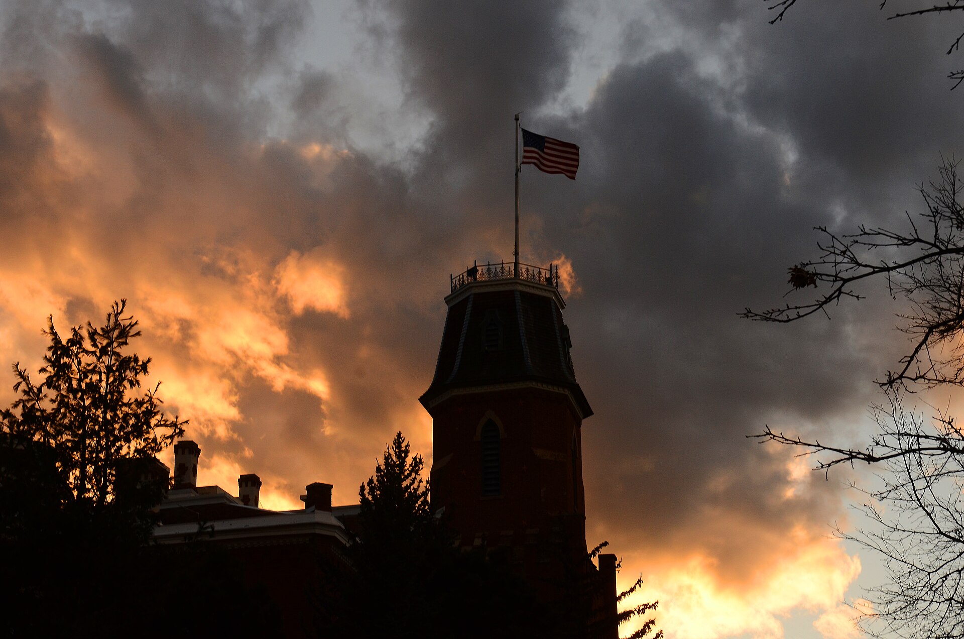 Old Main tower and flag at sunset on the University of Colorado Boulder campus