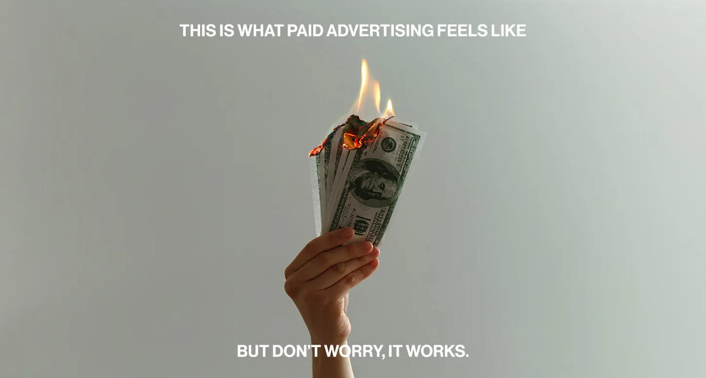 A graphic design of a hand holding money on fire with the words, "this is what paid advertising feels like but don't worry, it works."