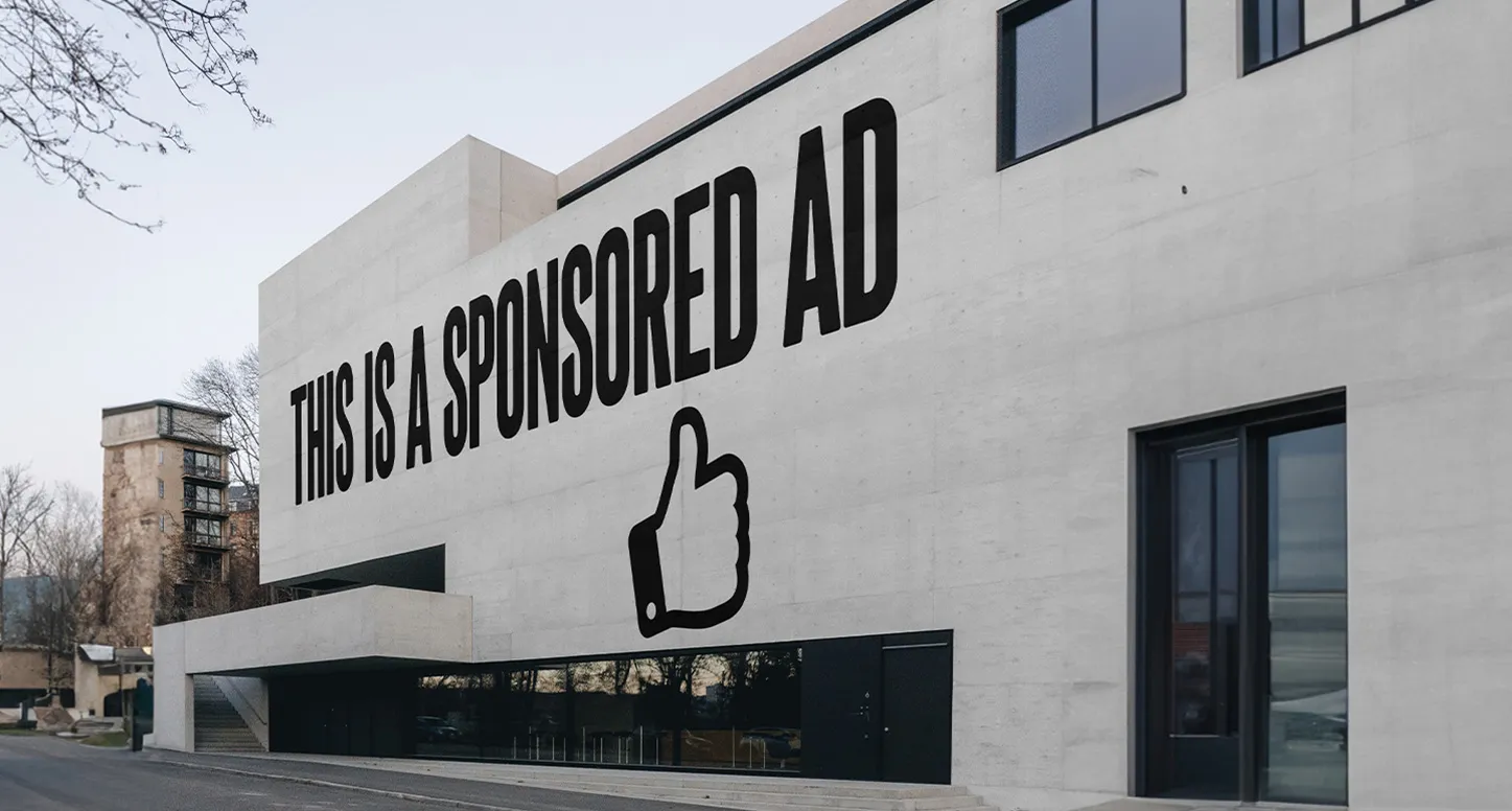 A mural on a white cement building that says "this is a sponsored ad"