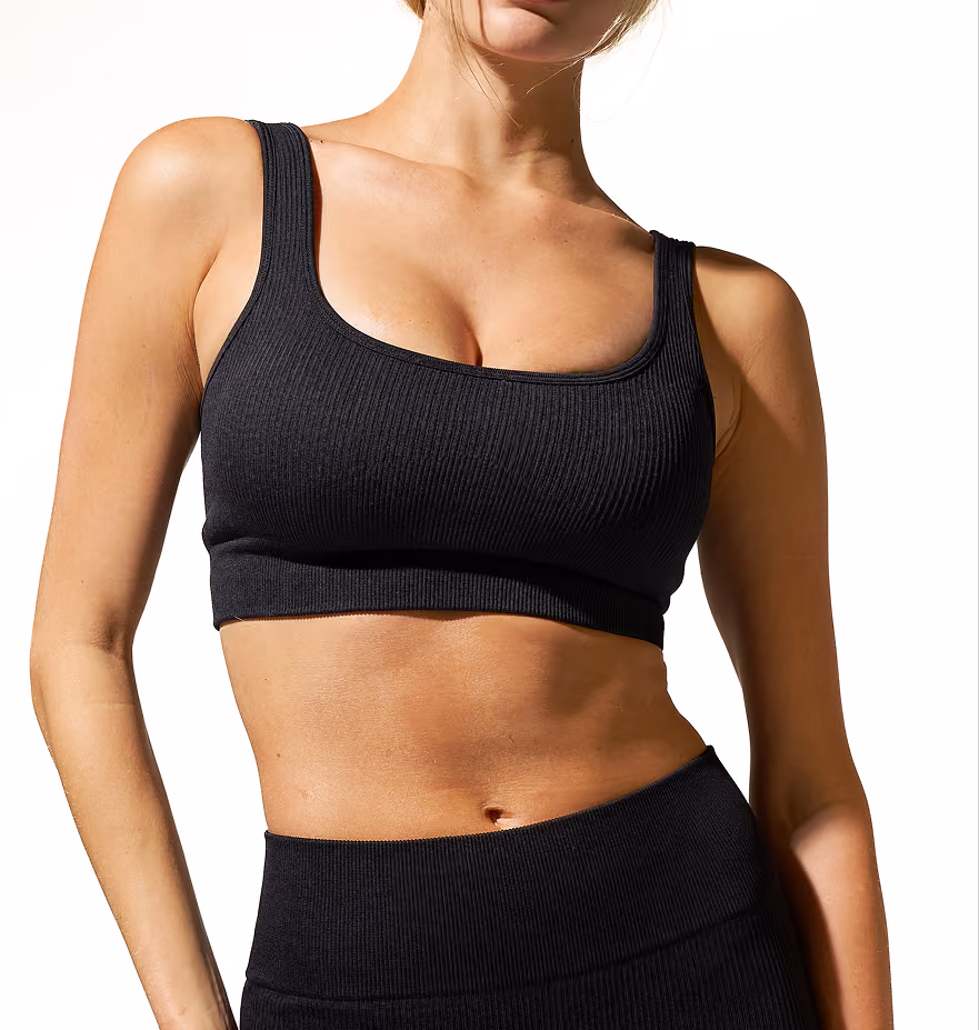 Woman wearing black ribbed athletic crop top and high-waisted leggings, shown from shoulders to waist against white background.