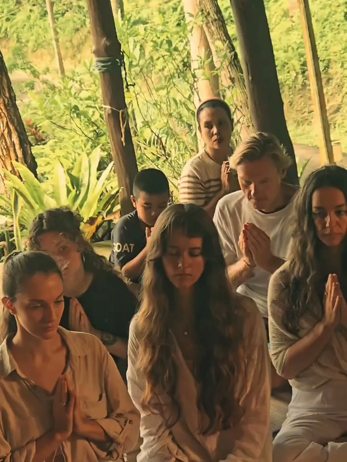 Residents seated with hands together during a blessing ceremony with local monks