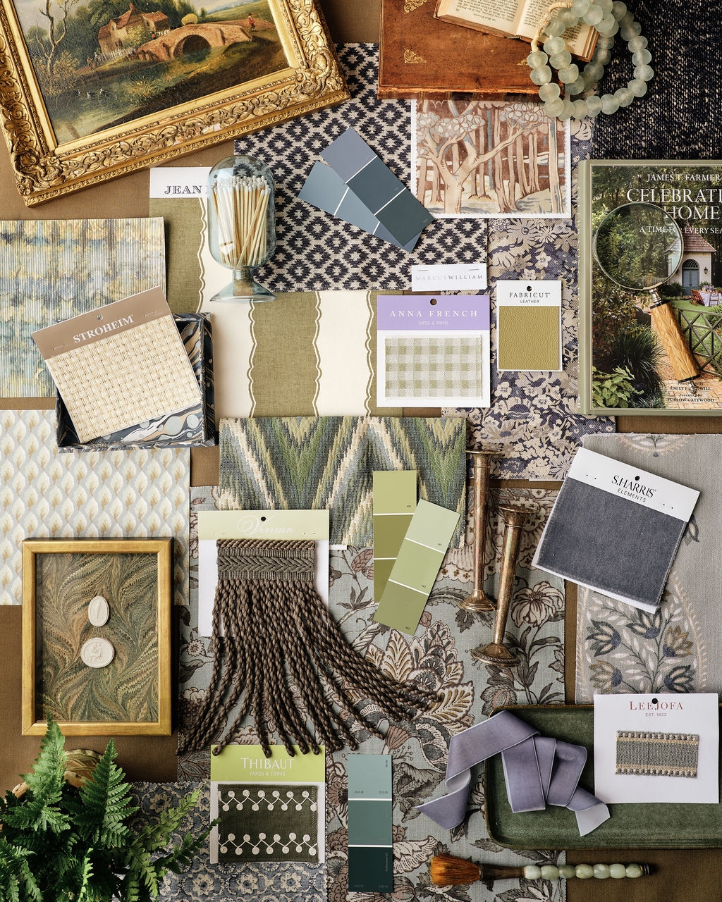 Flat lay of fabric swatches, wallpaper samples, framed art and green ferns