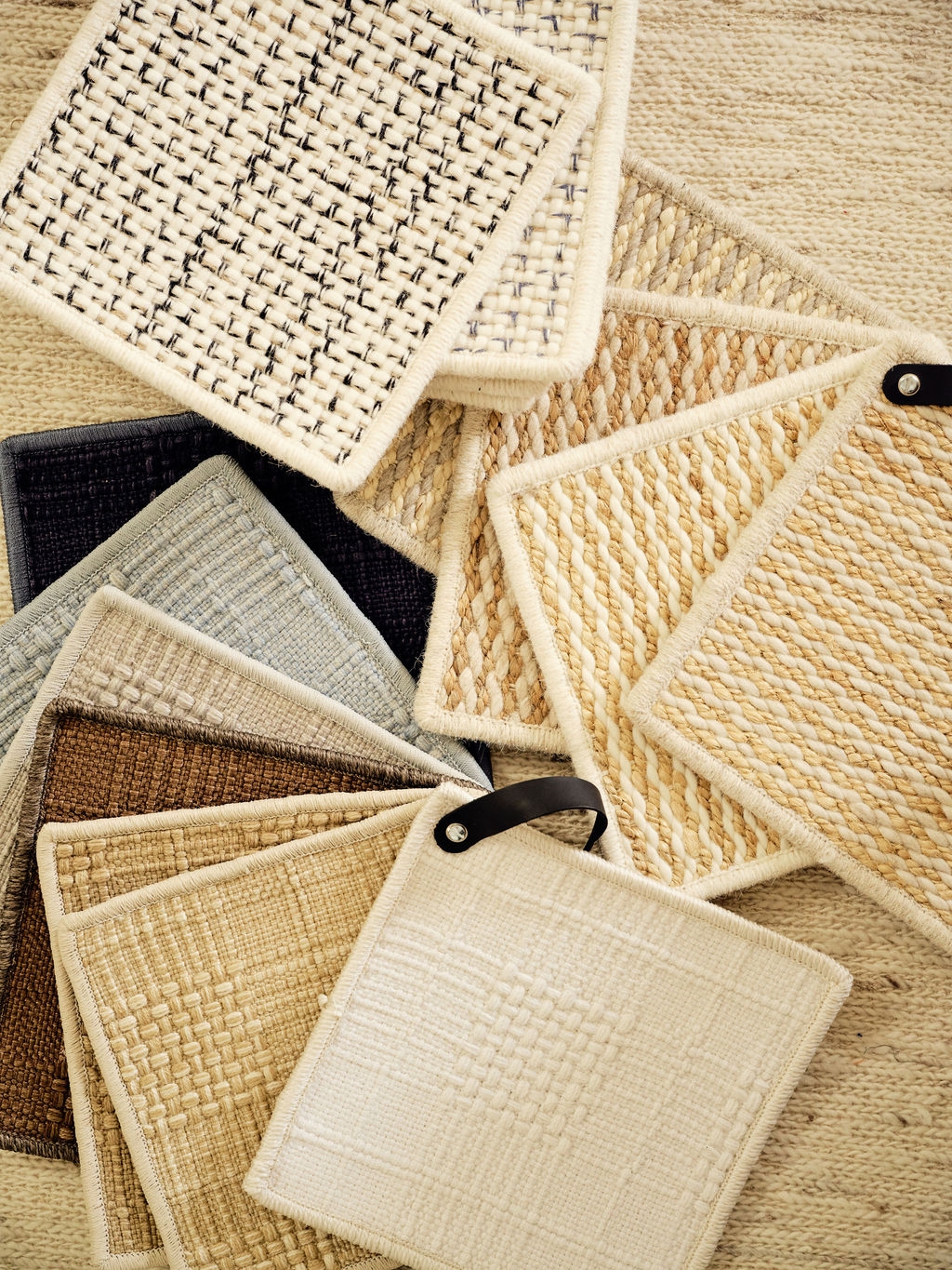Stack of woven natural-fiber rug samples in cream and sand