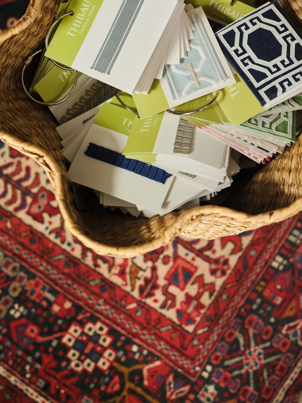 Basket of trim and fabric sample cards on a red patterned rug