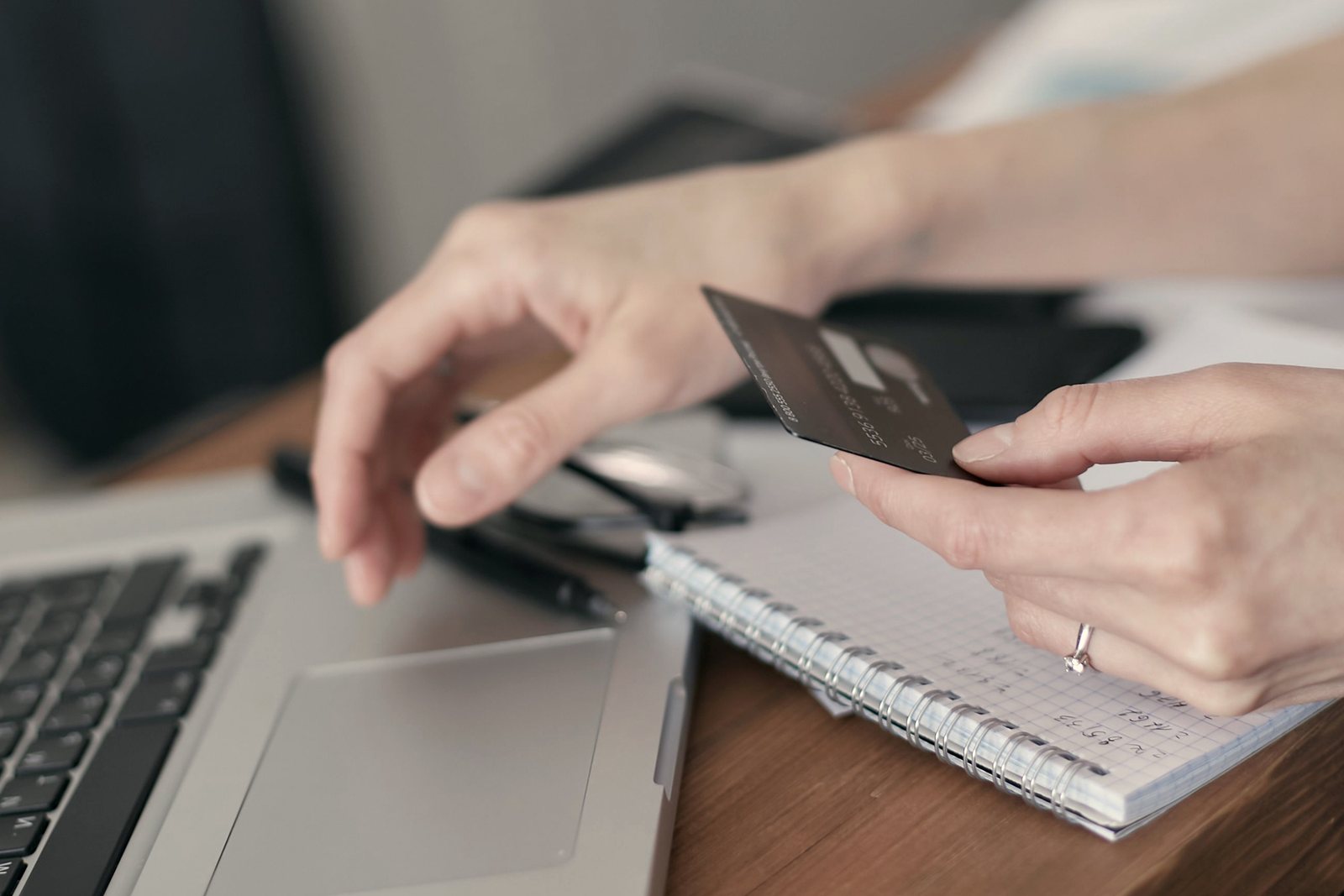 Hands holding a plain card beside a laptop during an online checkout