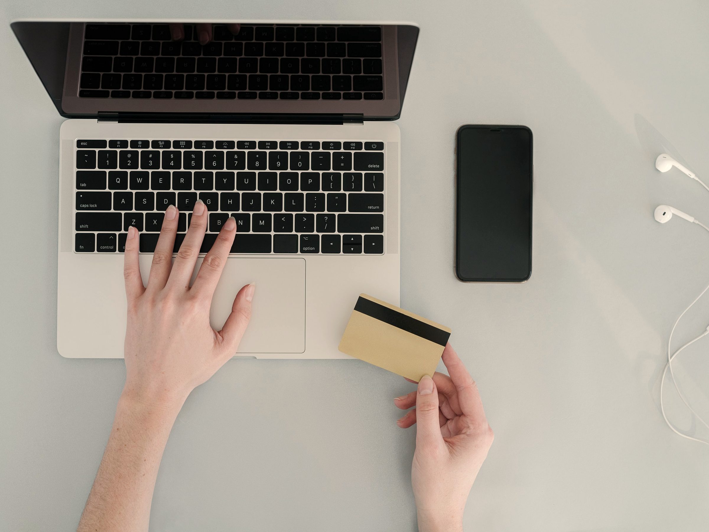 Hands at a laptop holding a payment card