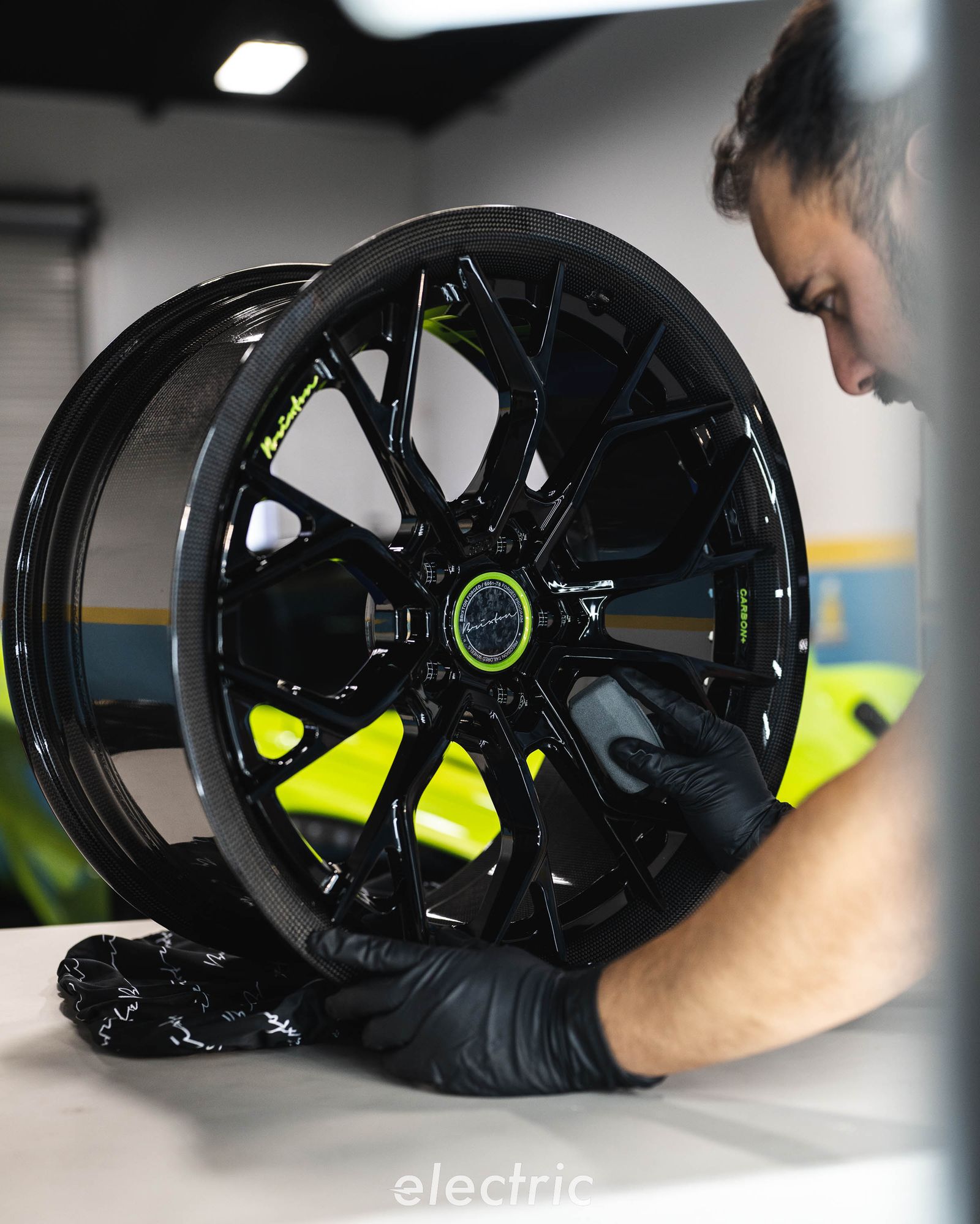 Technician handling a black forged wheel in the shop