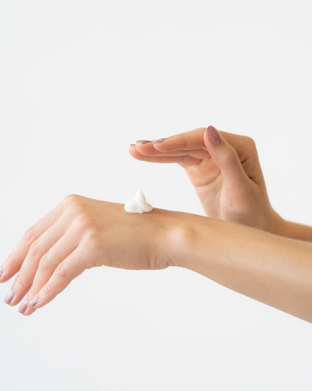 Hand with a dab of topical cream on the wrist, against a bright white background