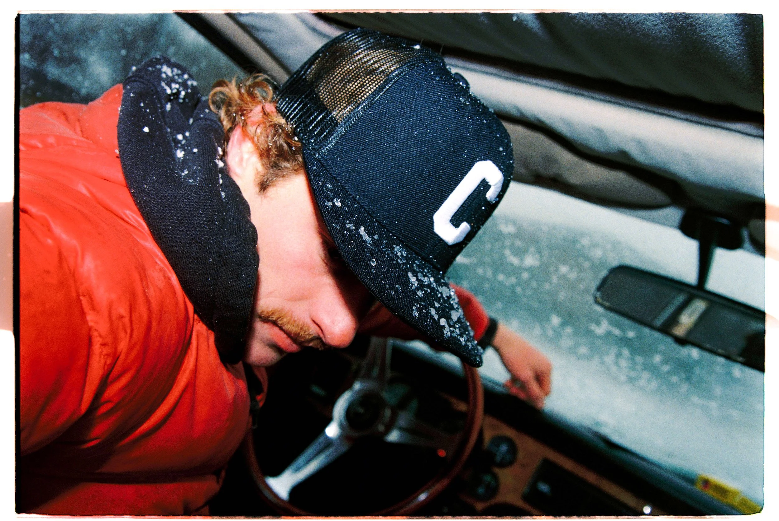 Traveler resting in the driver's seat during a snowstorm — CAO Winter 25