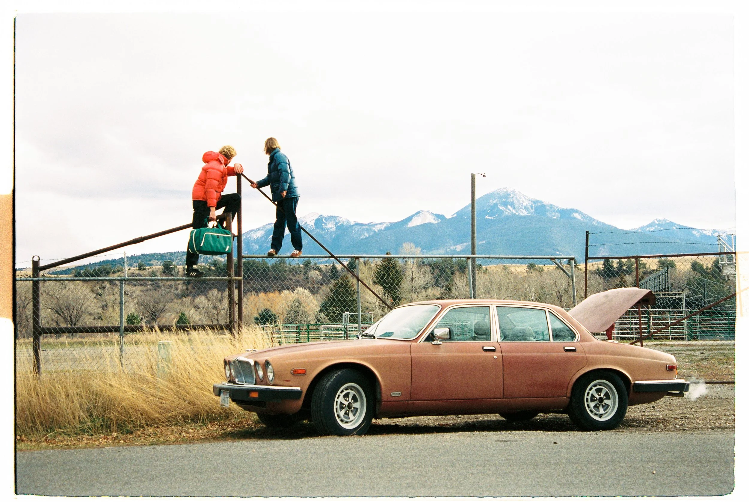 Children on a playground below a mountain range beside a vintage car — CAO Winter 25