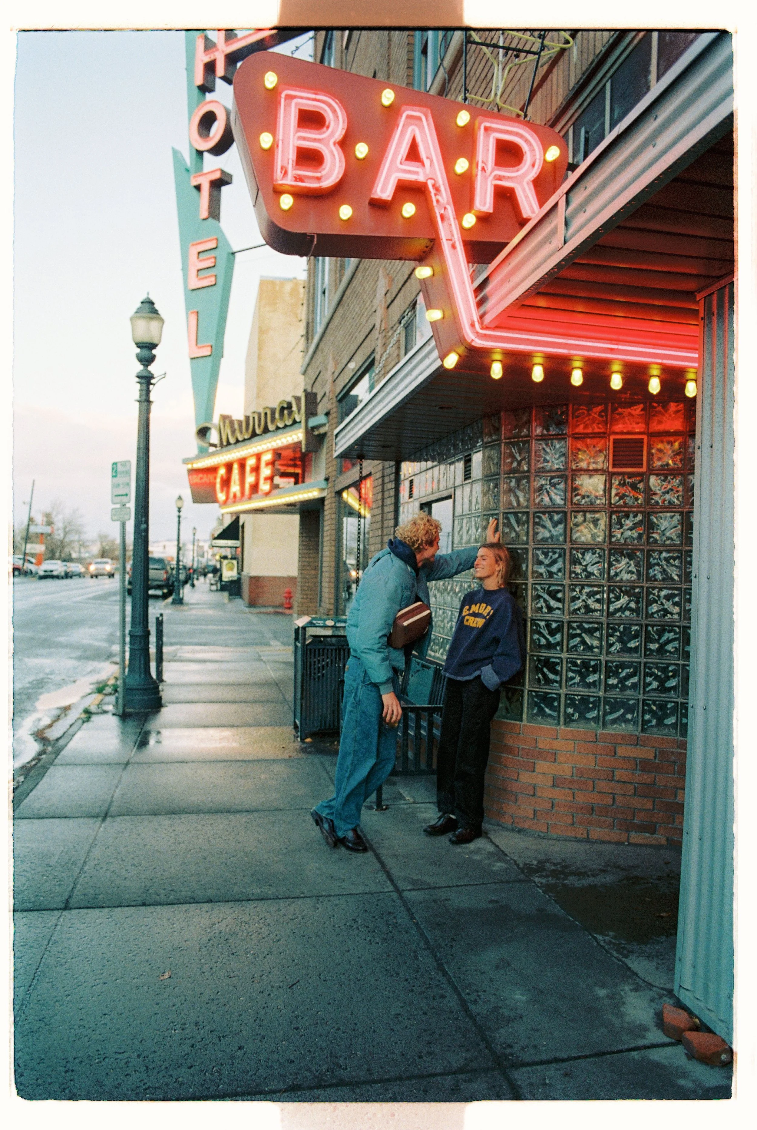 Couple outside a neon-lit bar on a city sidewalk at night — CAO Winter 25