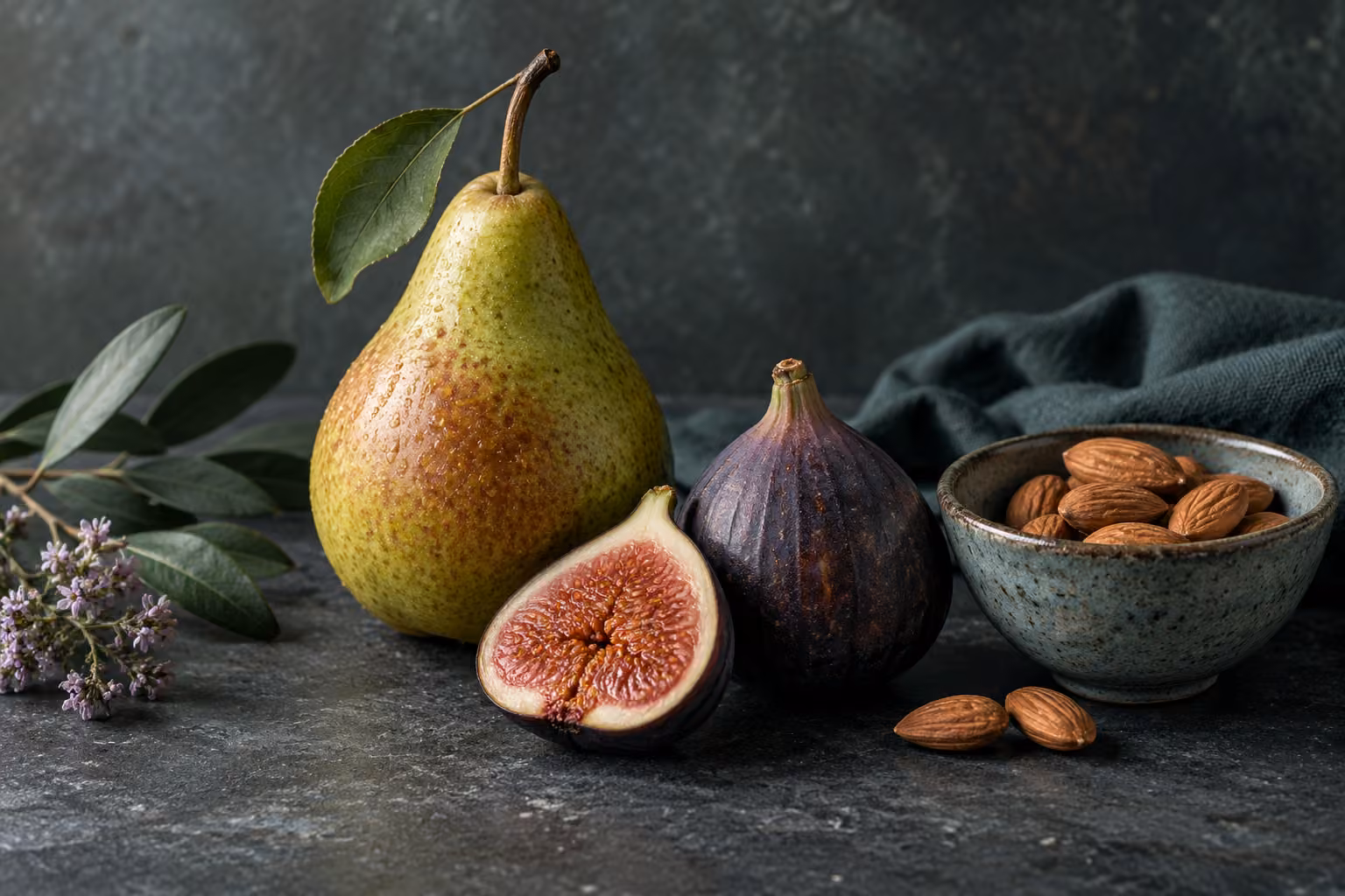 A pear, figs and a bowl of almonds on a table.