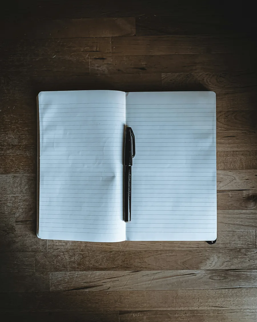 Stock photograph of a blank lined notebook and black pen.
