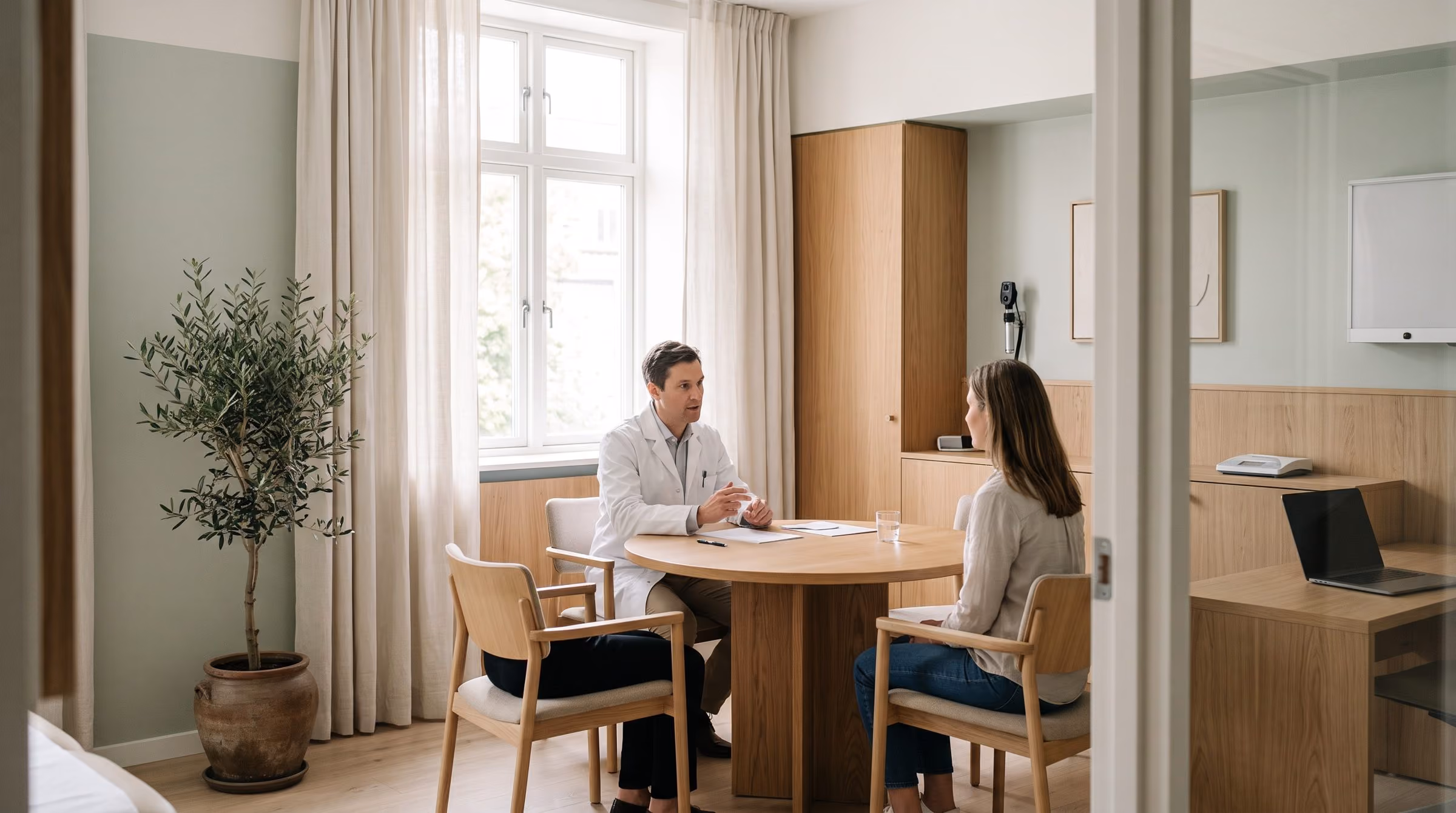A specialist talking with a patient at a table in a bright Oriel consultation room