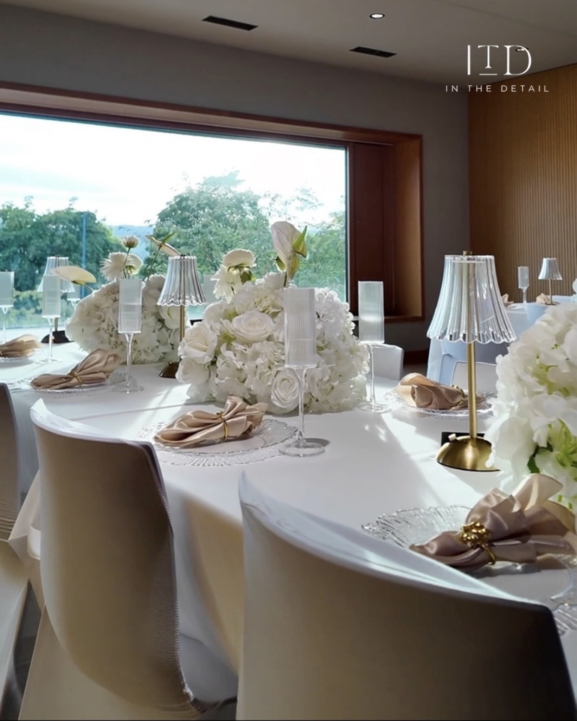 Hochzeitstisch von ITD mit weissen Blumen, champagnerfarbenen Servietten und goldenen Tischlampen.
