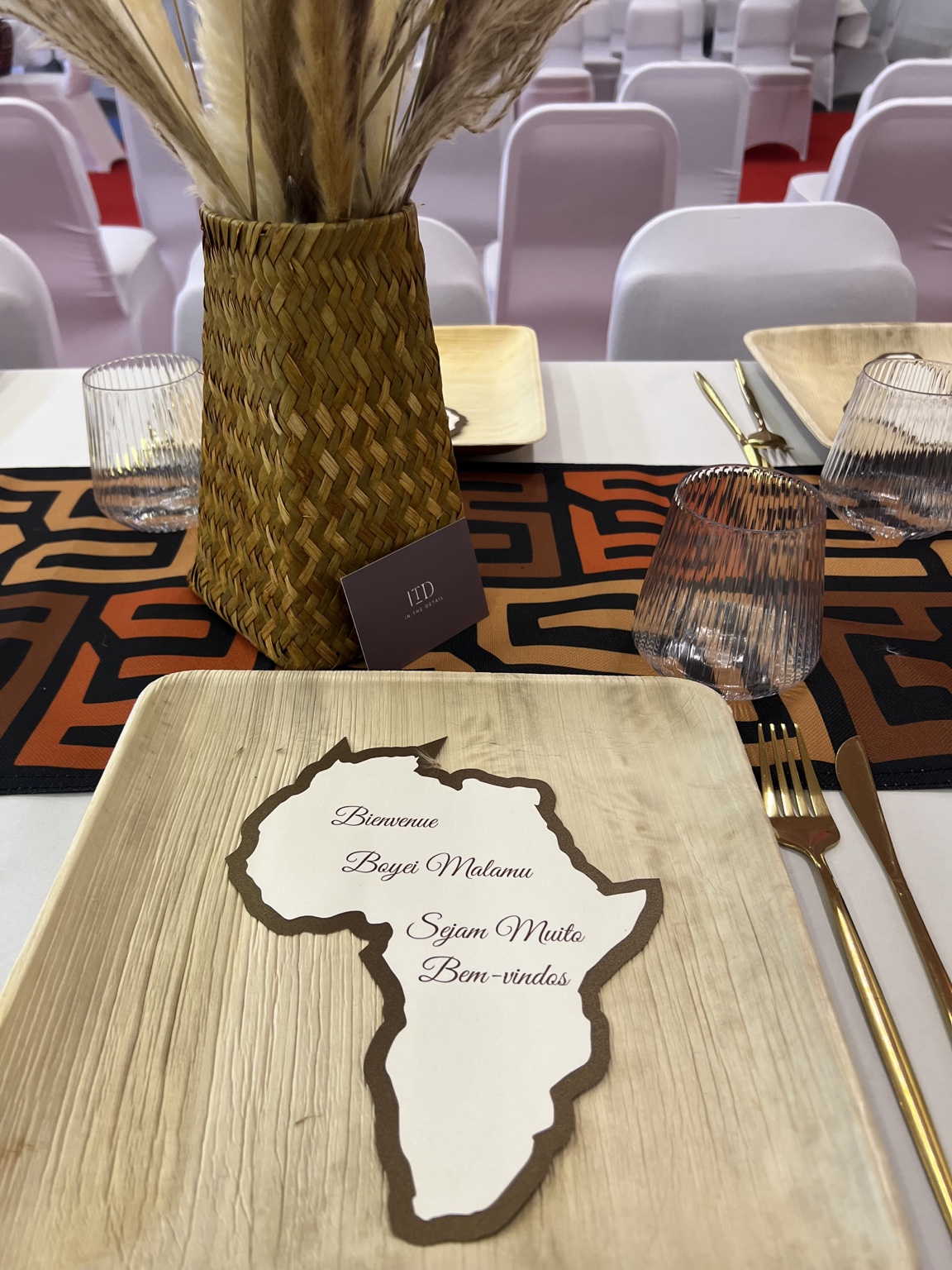 Tischgestaltung mit Pampasgras, geflochtener Vase und Willkommenskarte in Afrikaform.