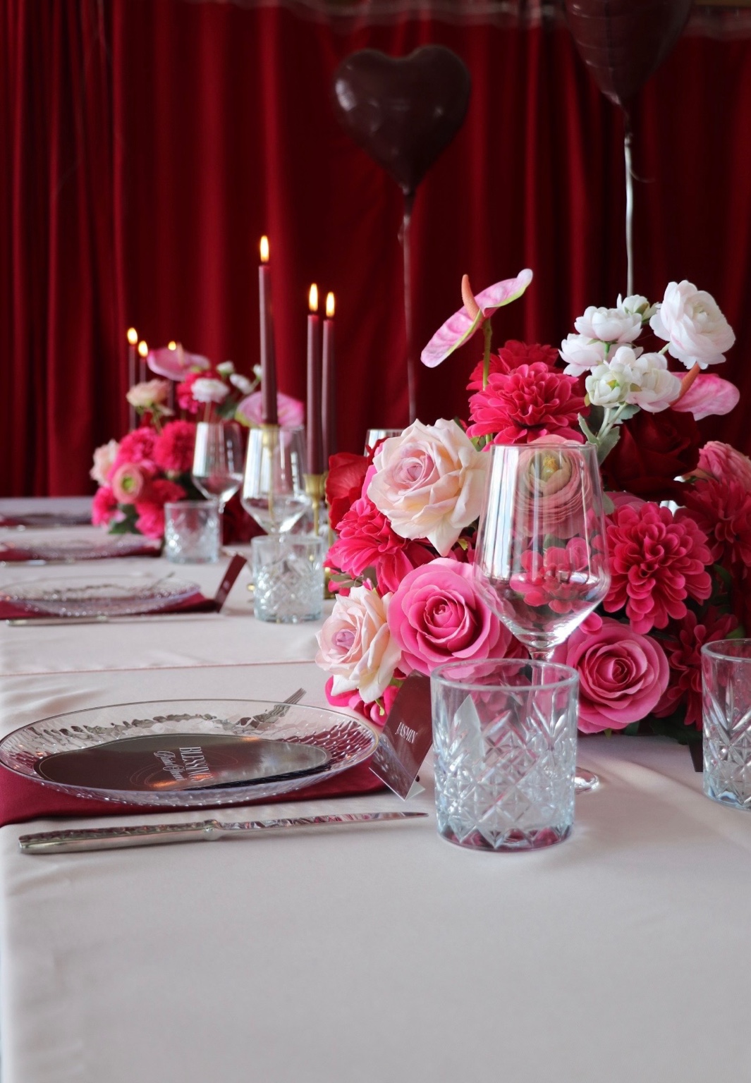 Bridal-Shower-Tafel mit rosa und bordeauxfarbenen Blumen und Kerzen.