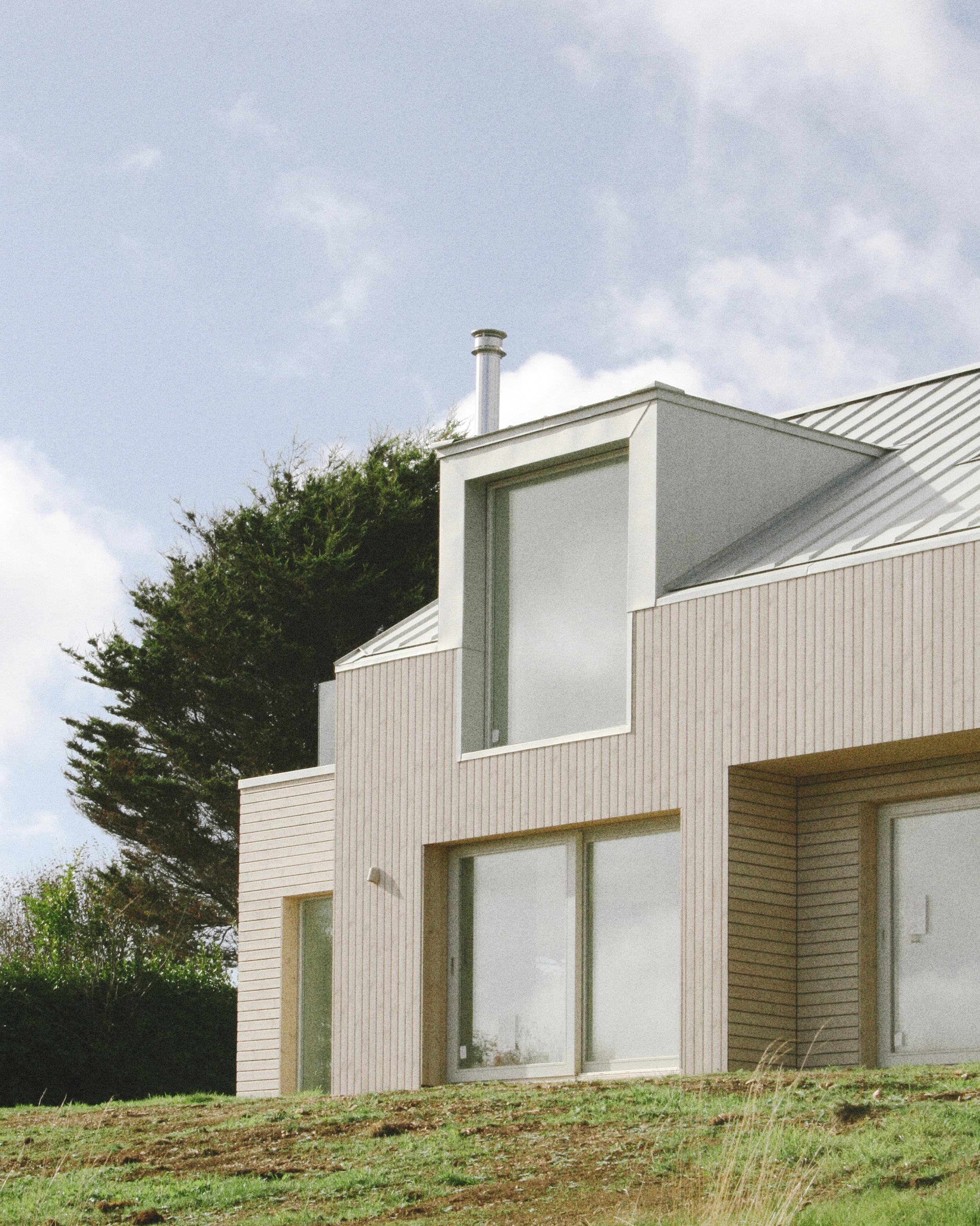 Timber-clad house with a zinc roof and large dormer windows