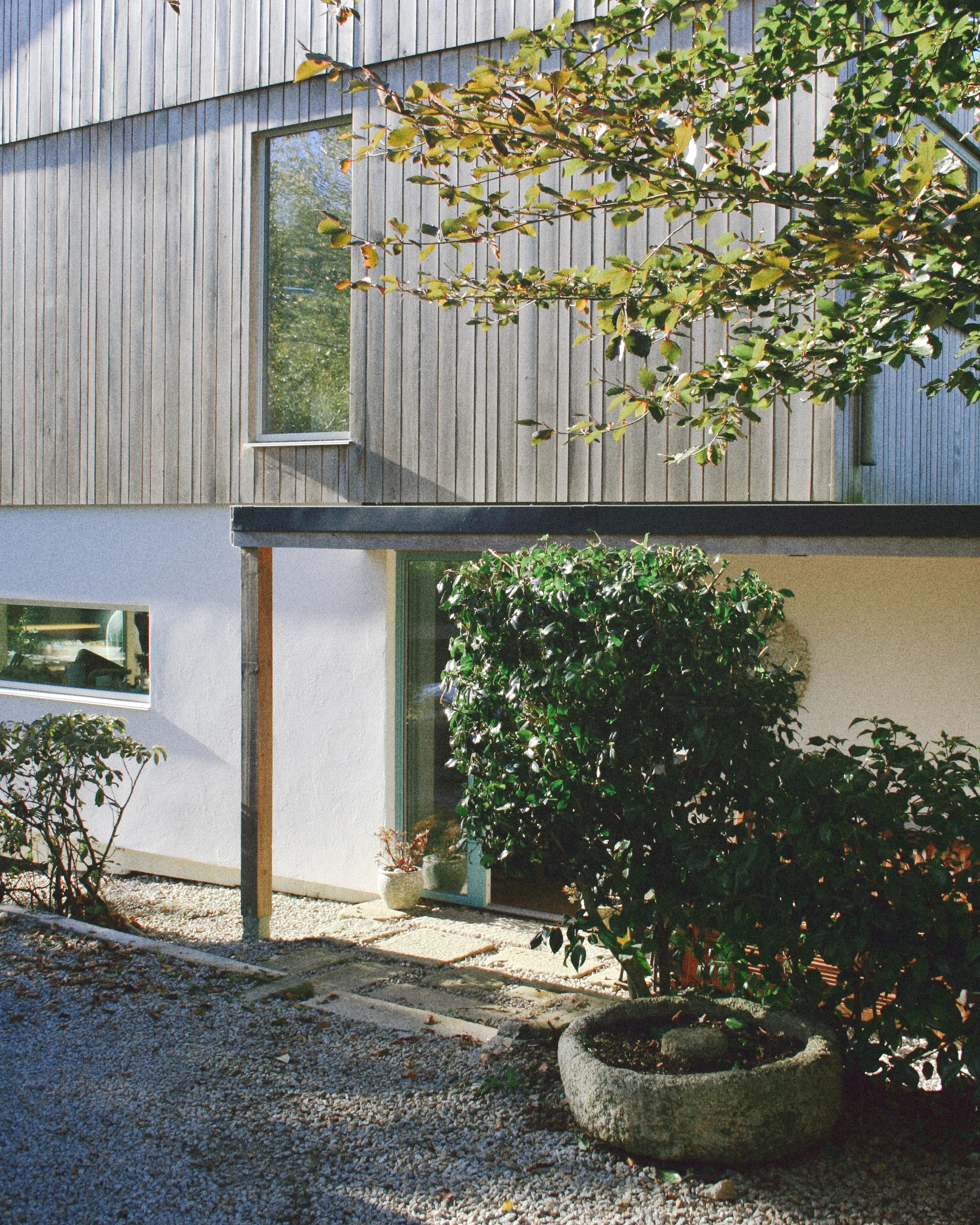 Converted stone barn with a red roof and timber door on a street corner