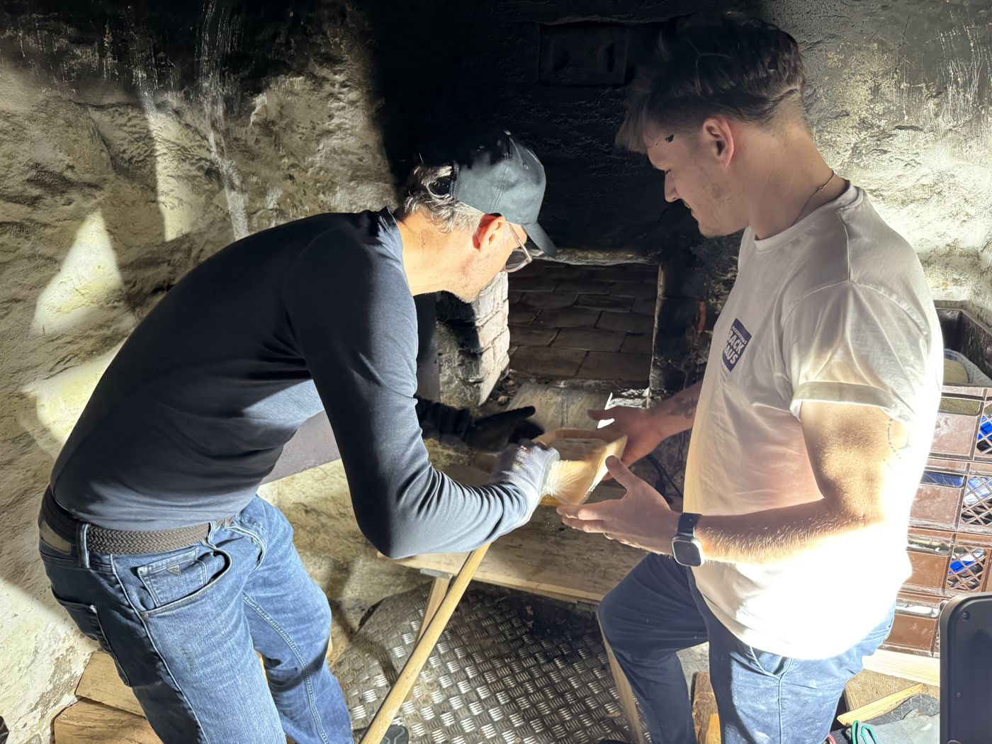 Bäckermeister und Auszubildender gemeinsam am historischen Holzbackofen