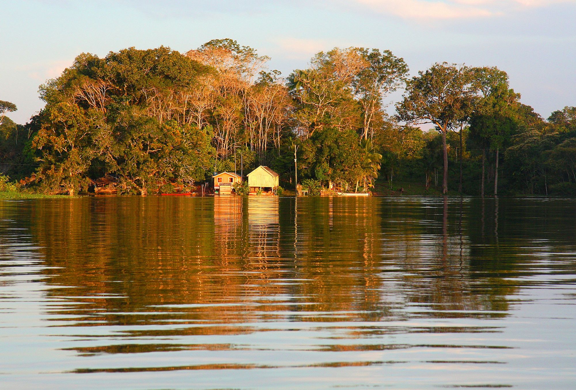 Maisons riveraines au coucher du soleil en Amazonie