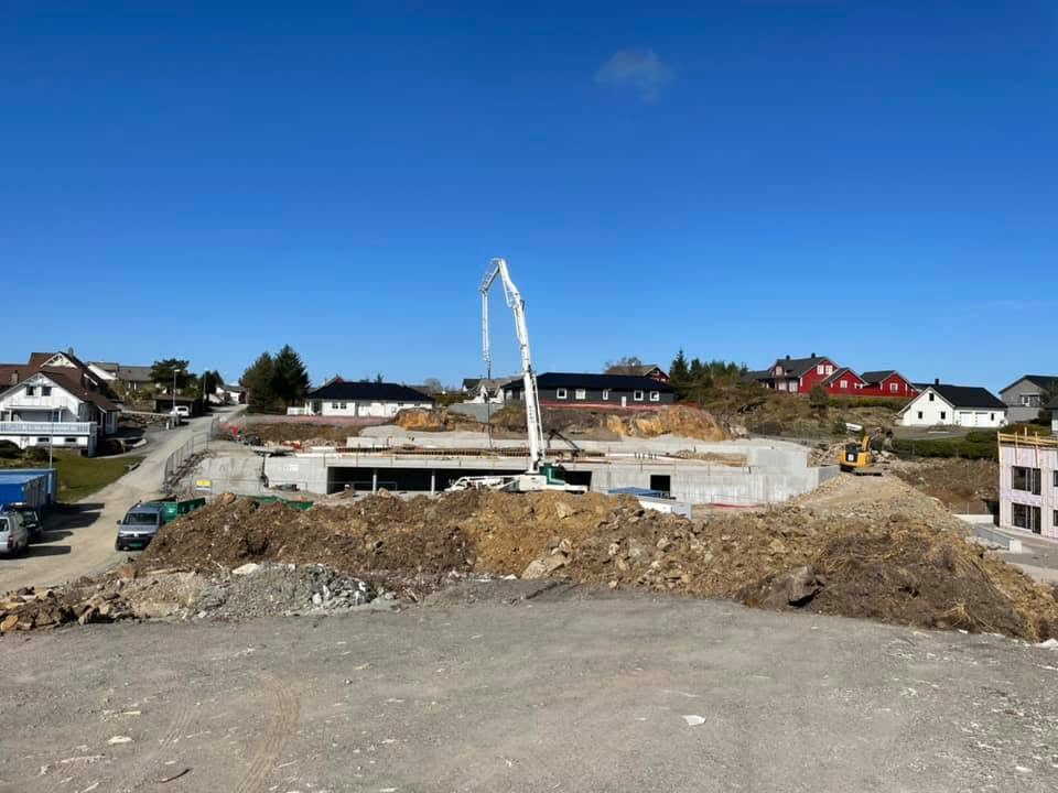 Grunnmurer på en boligbyggeplass med betongpumpe i bakgrunnen.
