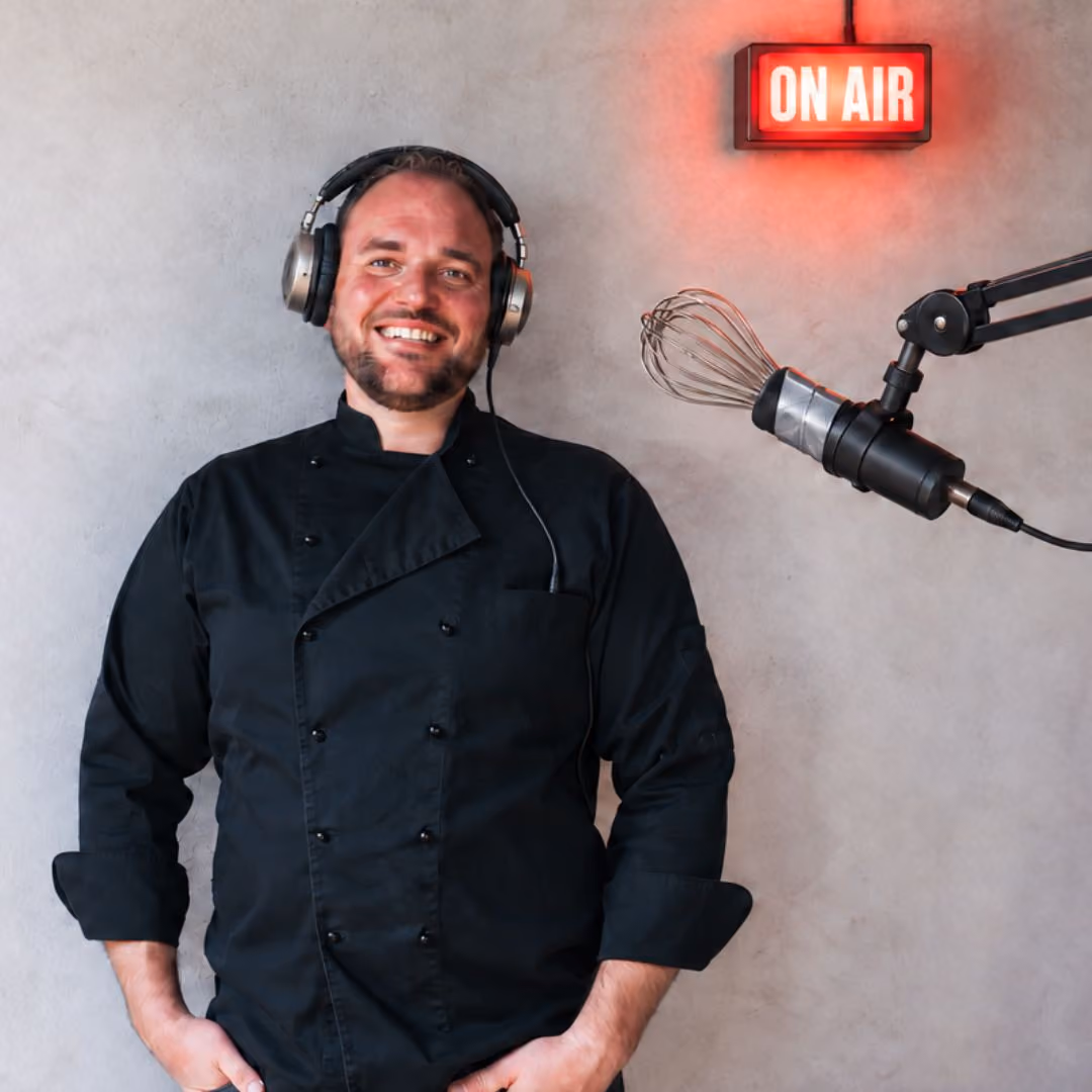 Harold Engelen in koksbuis met koptelefoon, naast een microfoon met een garde en een brandende ON AIR-lamp