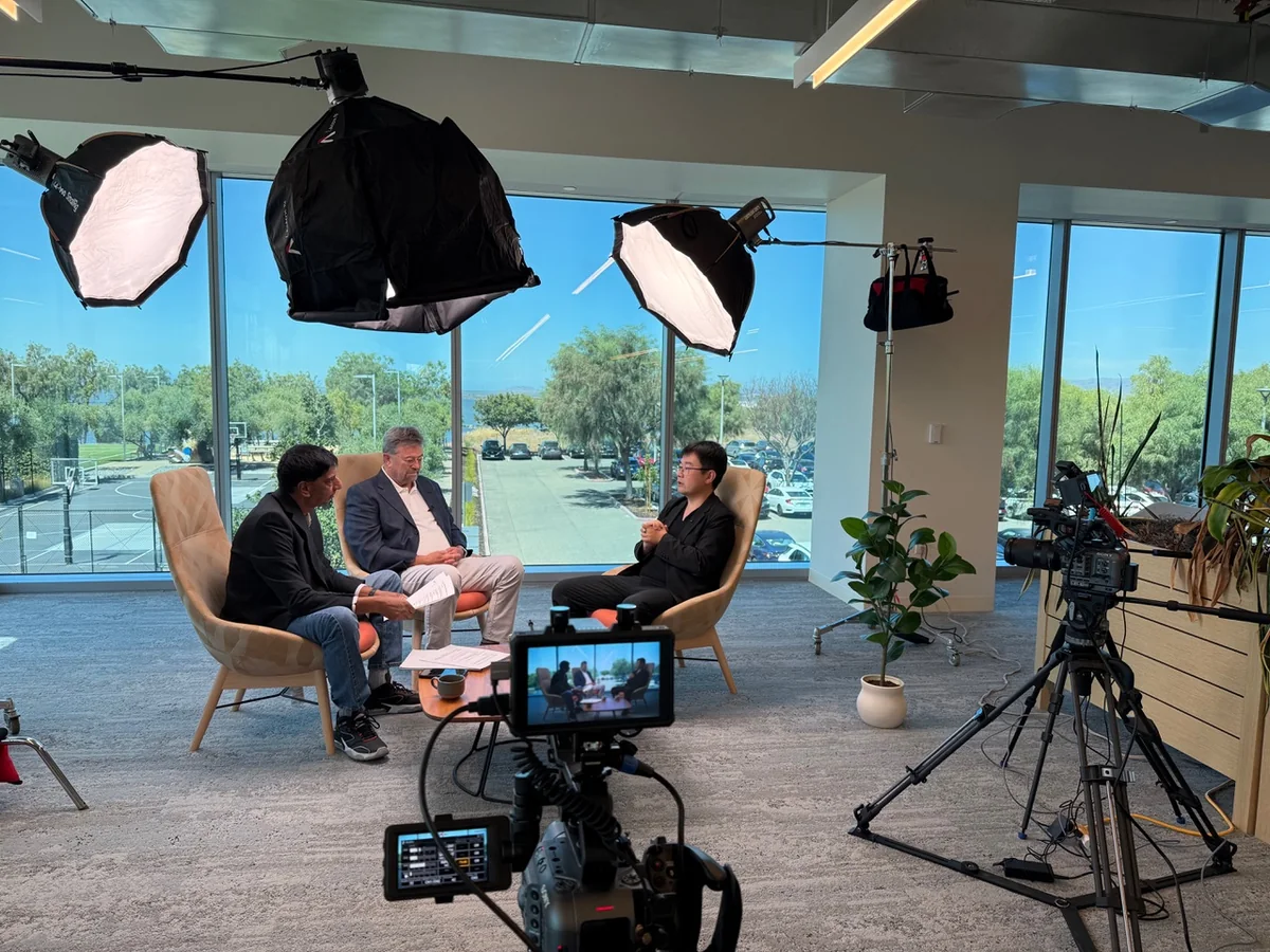 Camera and lighting team preparing a two-person interview on location.