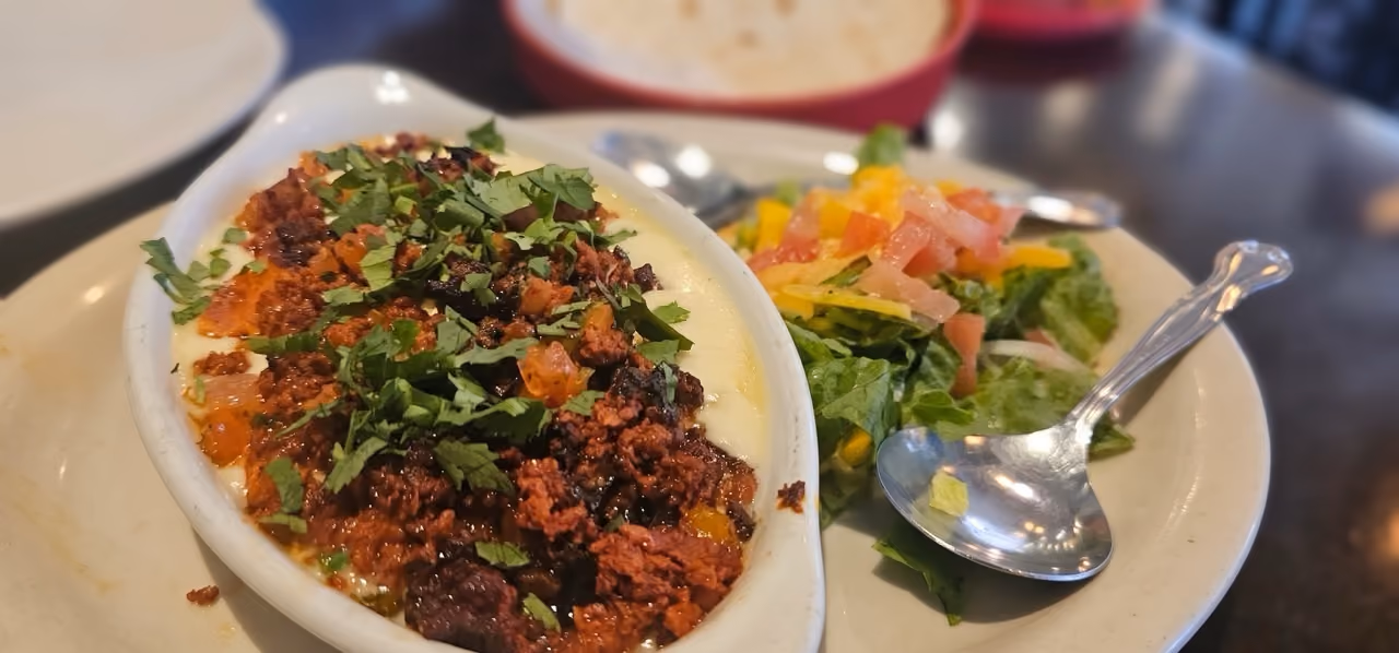 A plate of food with a bowl of meat and a salad.