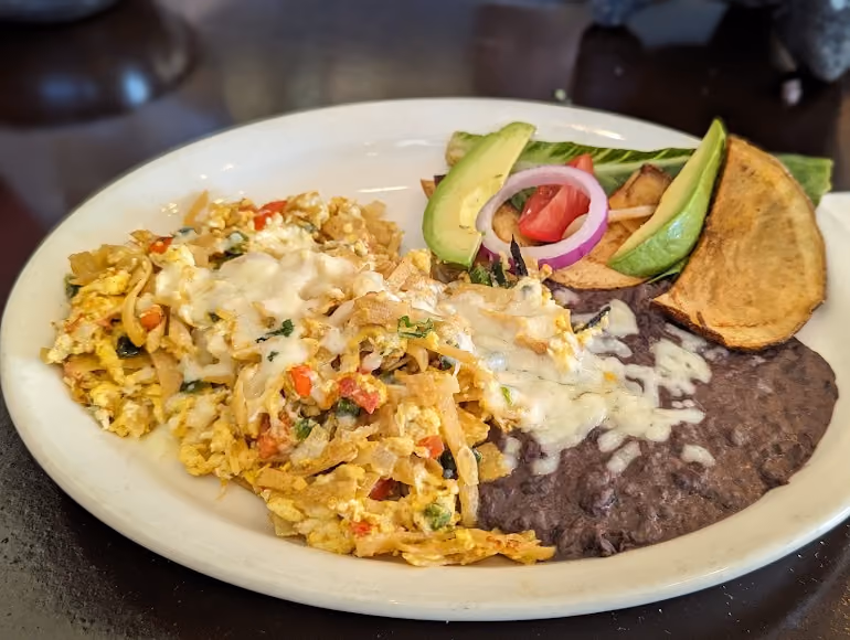 A plate of food with a slice of pizza and a side of guacamole.