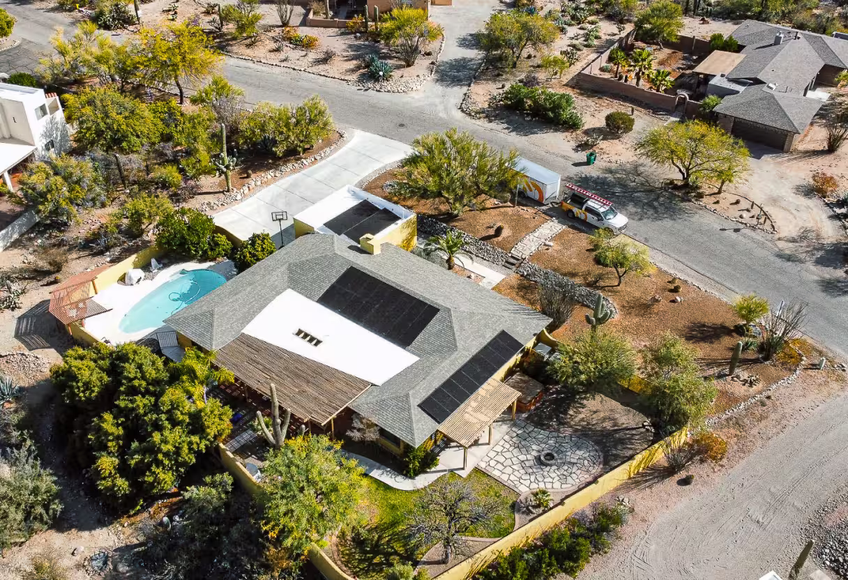Aerial view of a home with rooftop solar and a pool