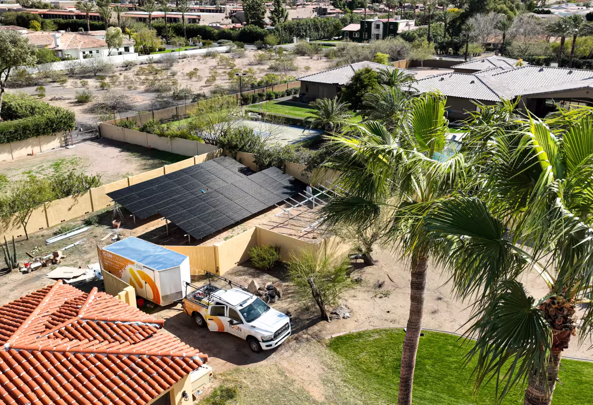 Ground-mounted solar array beside a home, with an Icon Power truck